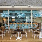 Above, a picture of Primrose’s indoor seating area. Parachute Pizza’s menu will also include oysters, salads, wines, garlic knots, and wines. Photo Credit: Primrose’s Facebook page