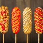 two hands fresh corn dogs spread