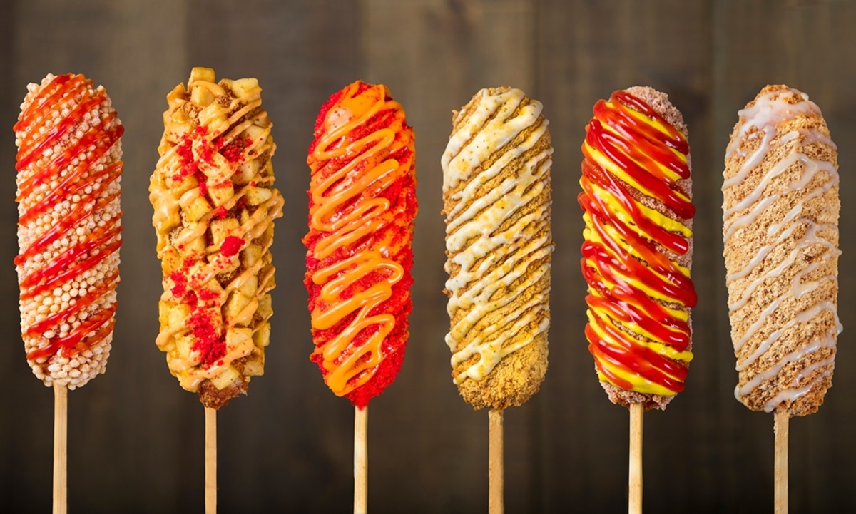 two hands fresh corn dogs spread