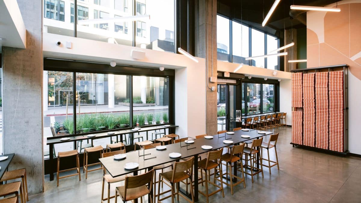 The layout features a 14-seat communal table at the center and 19 counter seats along the floor-to-ceiling windows.