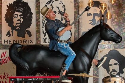Chef Brian Malarkey playing banjo sitting atop a horse statue