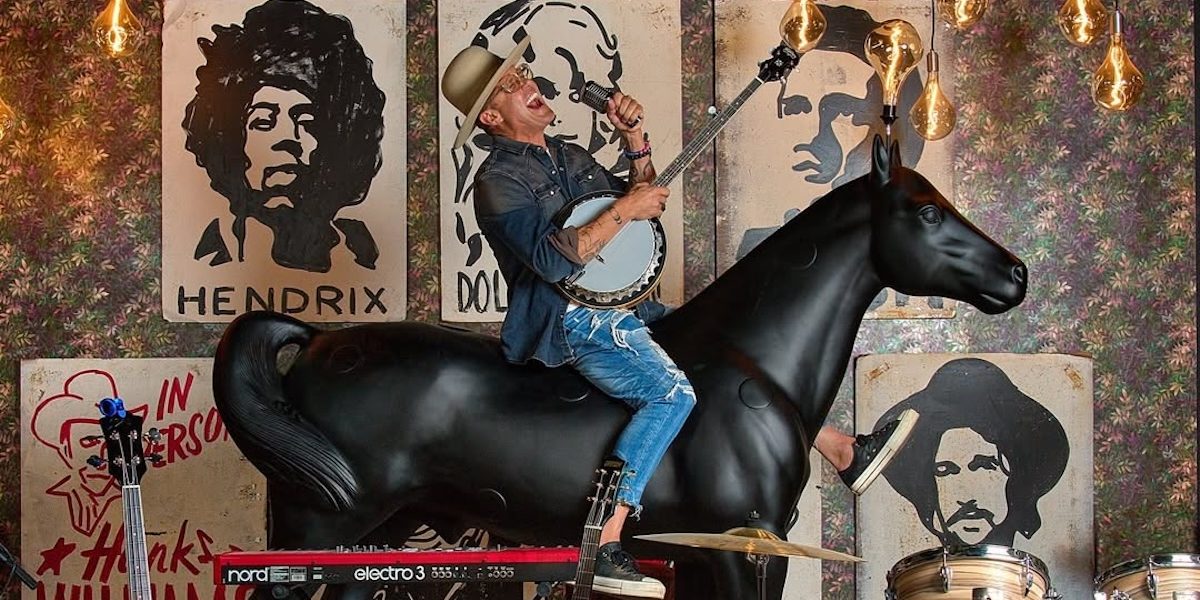 Chef Brian Malarkey playing banjo sitting atop a horse statue